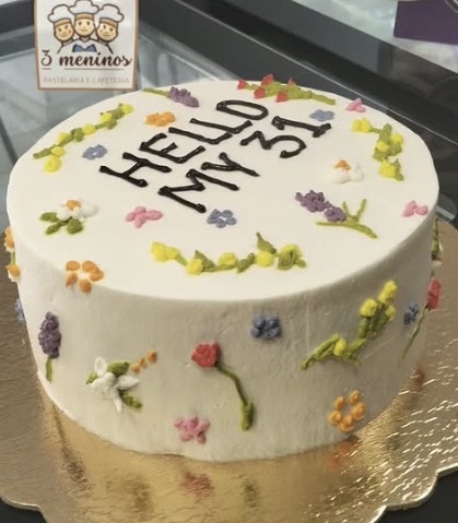 Bolo branco com flores desenhadas em creme e mensagem de aniversário