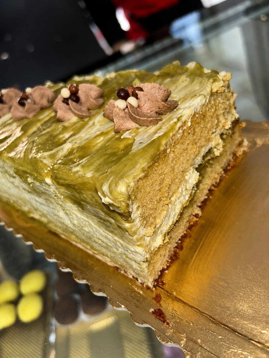 Fatia de bolo de pistache com cobertura verde e creme